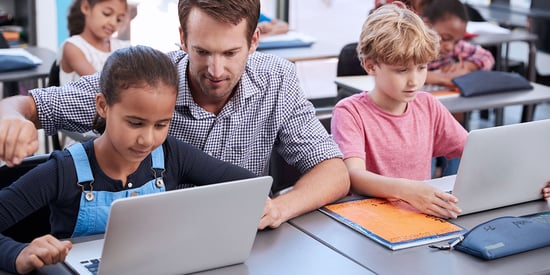 lifestyle-bluum-teacher-helping-kids-laptops-social
