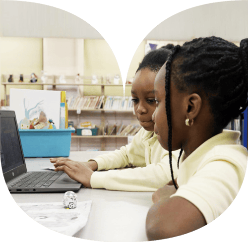 Two girls working on a chromebook in class.