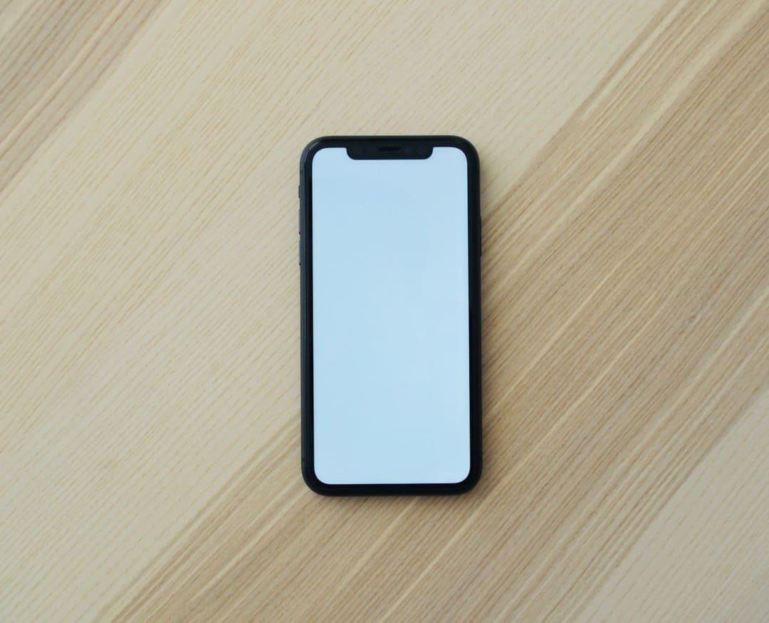 A cell phone with a white screen on a wooden table