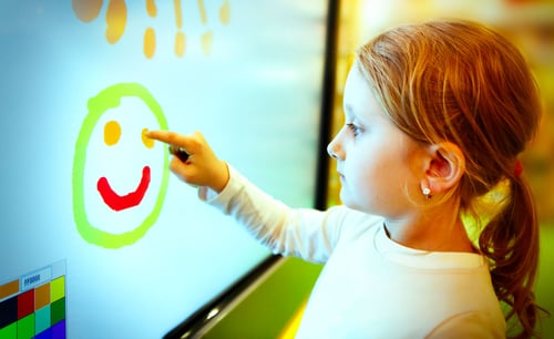 Girl drawing smiley face on interactive panel