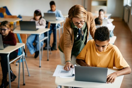 Student getting help with their laptop by their teacher