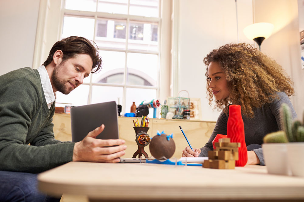 Man showing laptop lady taking notes