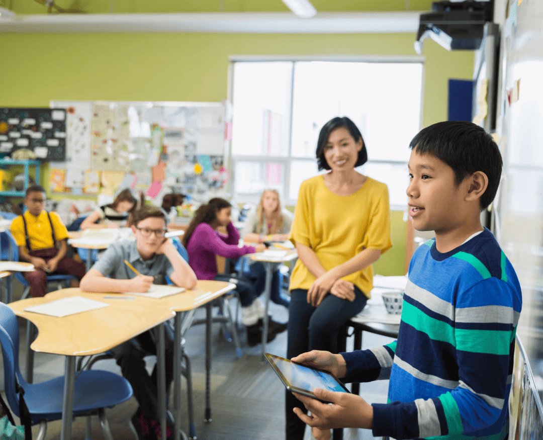 Boy presenting with a tablet in a classroom, demonstrating an activity that could be in a backward design lesson plan