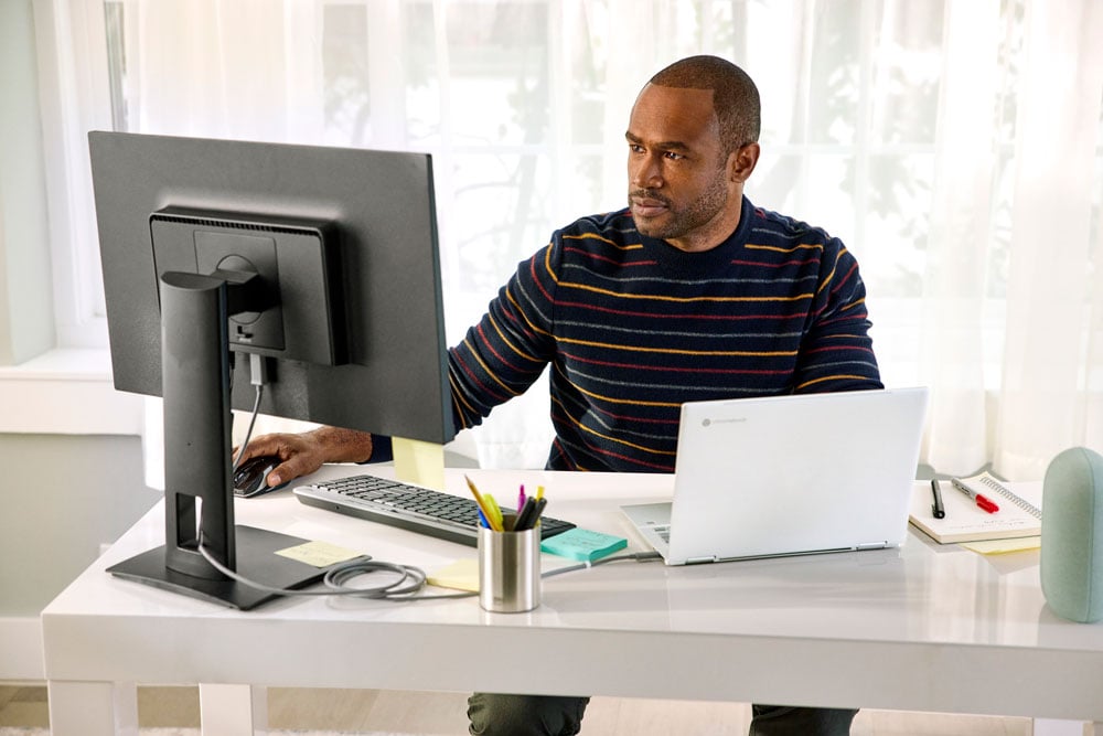 man working on a desktop and a chromebook